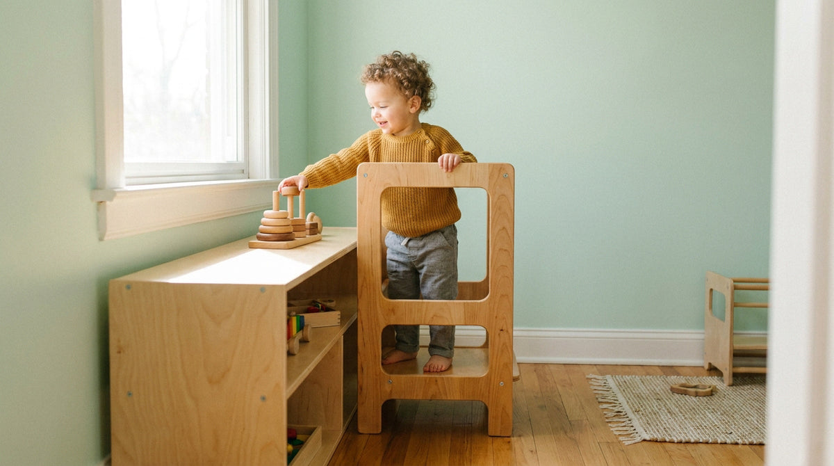 Enfant utilisant une tour Montessori en bois dans la cuisine